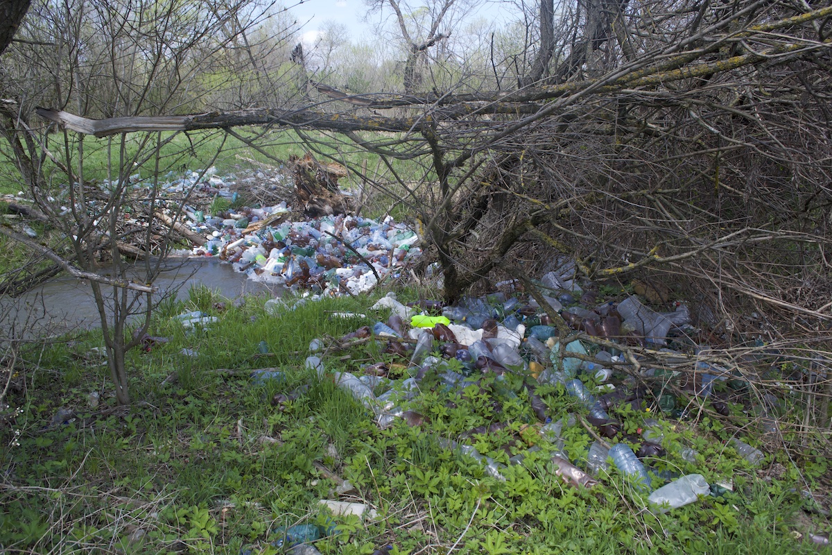 FOTO „Dezastru ecologic” pe Seviș – insule de PET-uri pe albia râului și un câmp plin de ambalaje și materiale de construcție