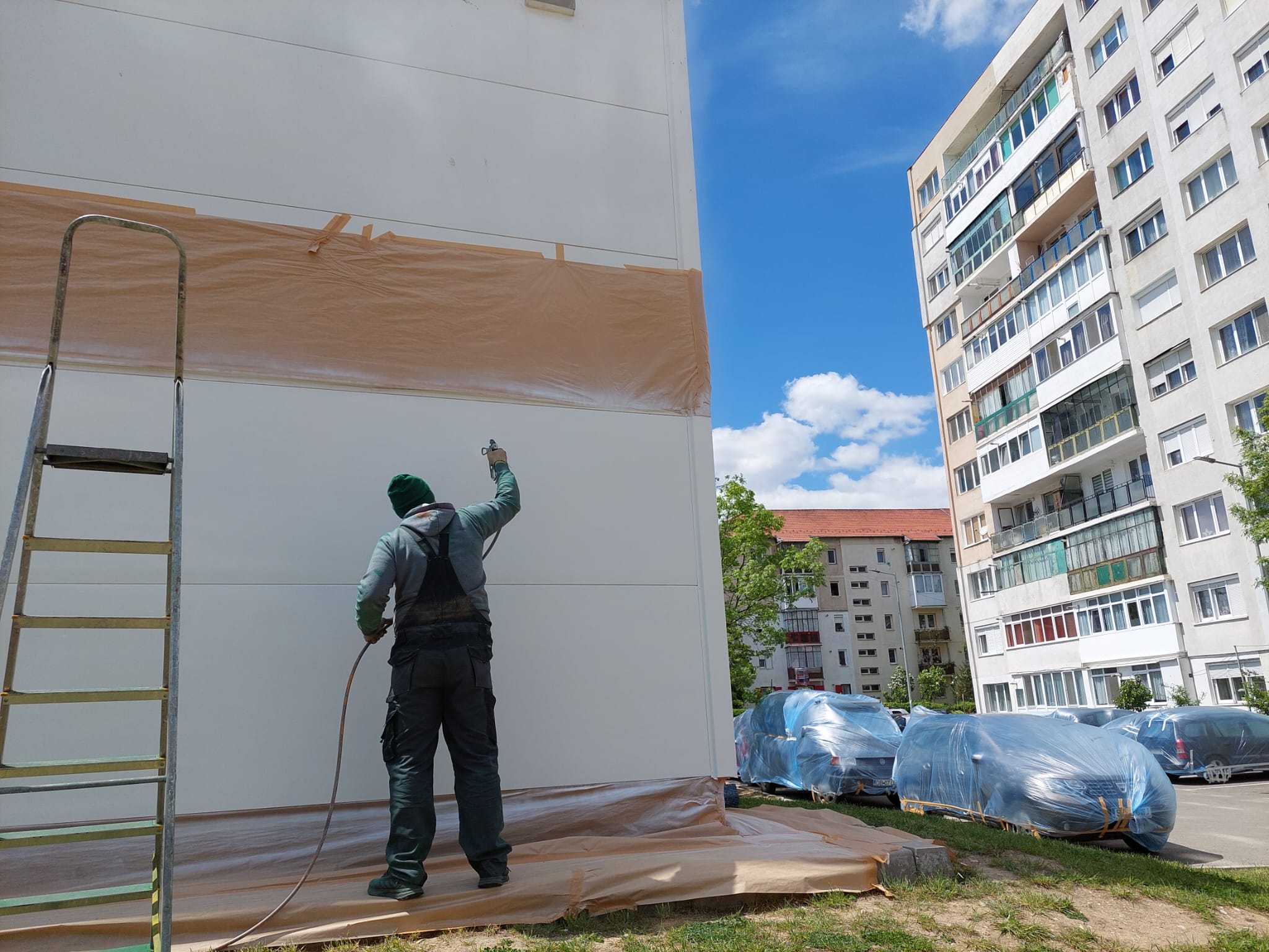 Exemplu de normalitate într-o parcare din Sibiu: o firmă din București a acoperit mașinile pentru a le proteja de vopseaua pulverizată