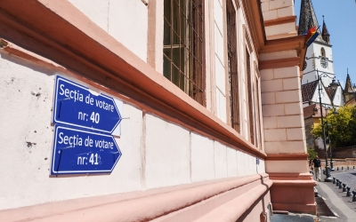 Urme electorale pe pereți: indicatoarele de orientare spre secția de votare, bătute în cuie pe fațada unei clădiri istorice