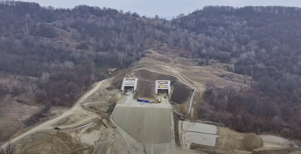 VIDEO Imagini din dronă cu dealul Momaia, sub care sunt săpate tunelurile de pe tronsonul 4 din autostrada Sibiu – Pitești. Lucrările s-ar putea încheia anul viitor