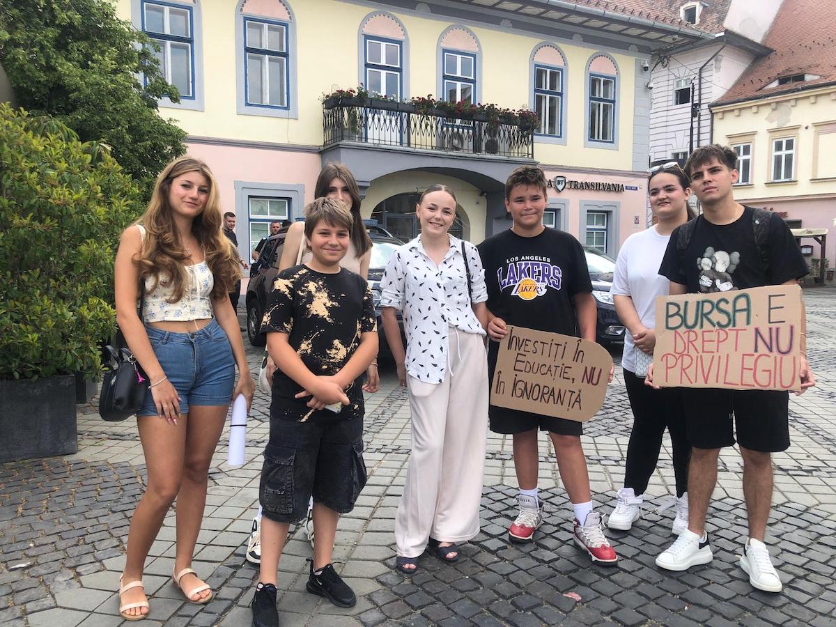 „Vor să taie din burse ca să ajute economia, dar nu pun pe primul loc că unele școli nu sunt bine dotate, nu există hârtie igienică și săpun la baie”. 15 elevi sibieni au protestat în Piața Mare împotriva tăierii burselor