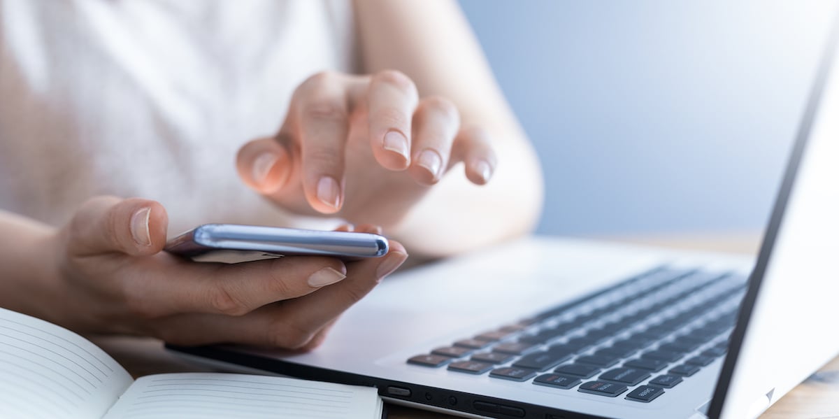 The woman works at home and uses a smart phone and a notebook laptop computer. Silhouette of a busy woman. She holds and using phone.