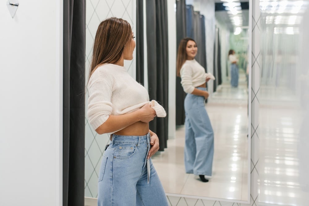 Young,Woman,Trying,On,Jeans,And,Checking,The,Fit,In