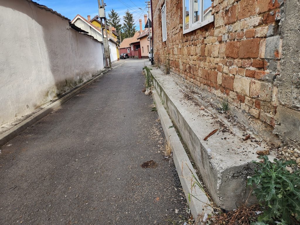 În 2021, când s-a modernizat strada Cucului, drumarii au turnat un prag de beton la baza clădirii, de teamă ca zidurile fără fundație să nu se prăbușească din cauza vibrațiilor. Foto: turnulsfatului.ro